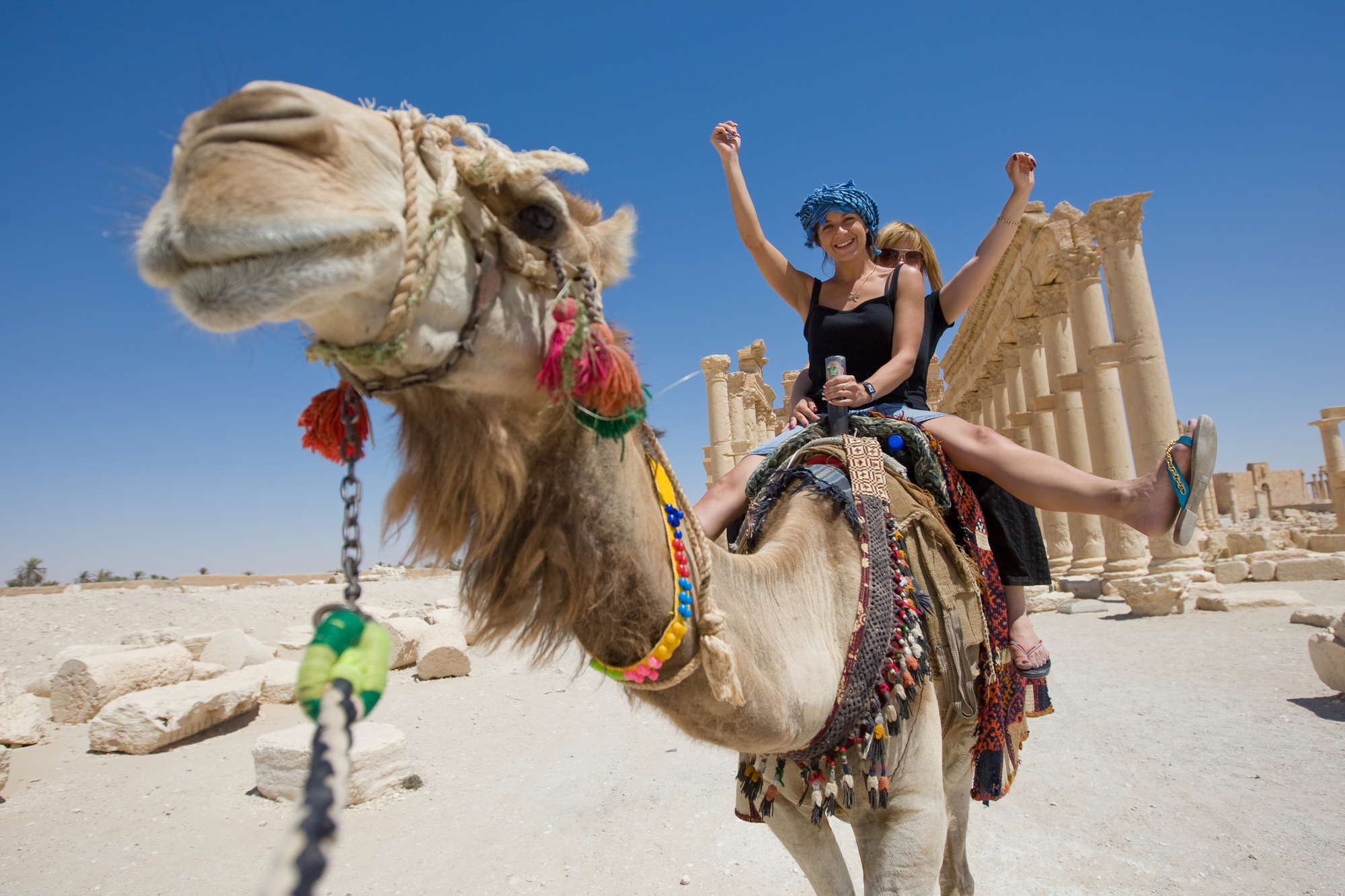 two girls riding on camel in desert