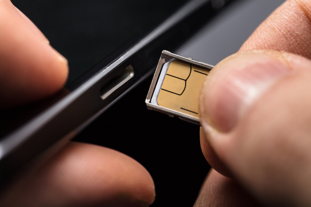 Close-up Of A Person Inserting A Sim Card Into The Back Of A Mobile Phone