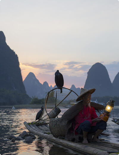 <span>Virtual cards</span> for online and in-store use A fisherman holding a lantern sits on a bamboo raft with cormorants, surrounded by Chinas dramatic karst mountains at sunset on a tranquil river.