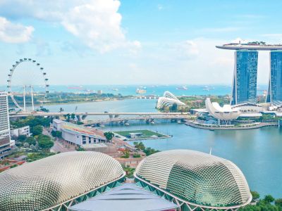 Aerial view of Singapore featuring the Marina Bay Sands hotel, Singapore Flyer Ferris wheel, Esplanade domes, and city skyline by the waterfront.