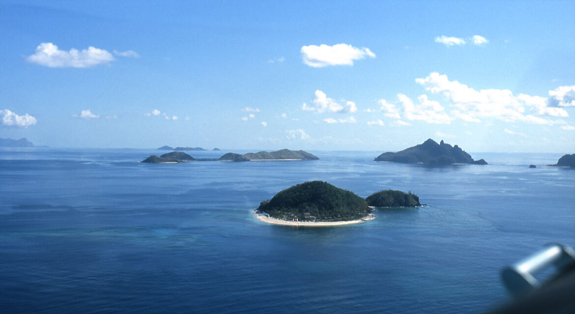 Aerial view of the Mamanuca Islands showing lush green islets surrounded by calm blue ocean waters.