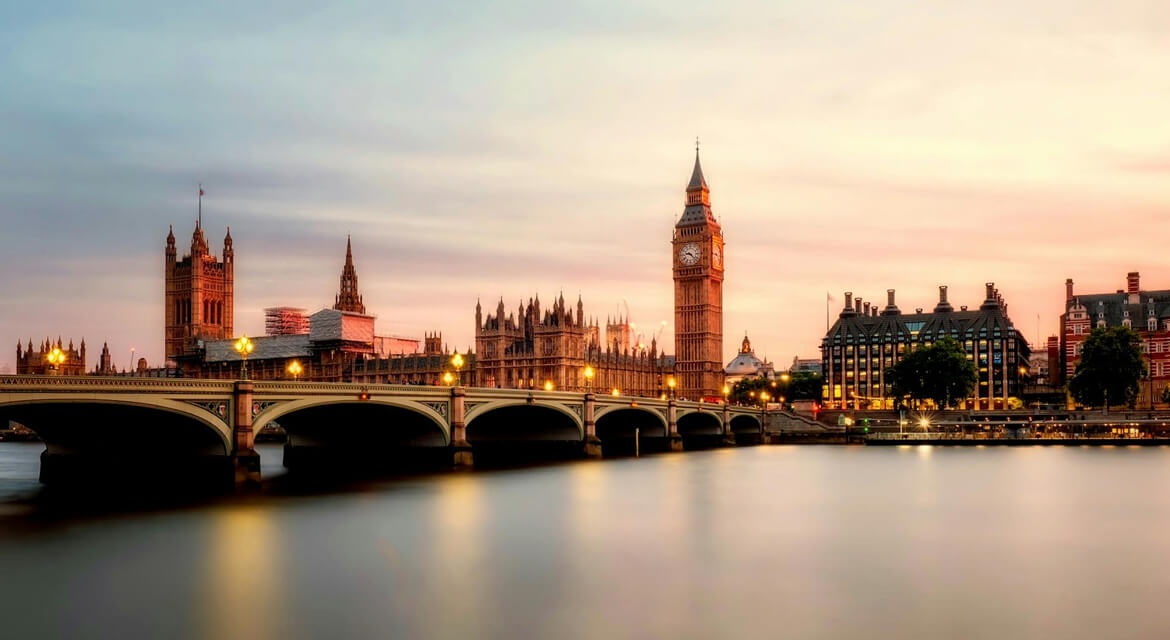 Scenic twilight view of Big Ben and the Palace of Westminster with warm lights reflecting on the River Thames and Westminster Bridge in London