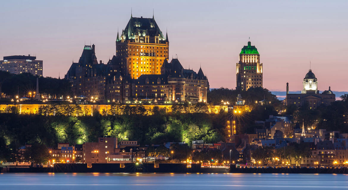 Twilight view of Old Quebec City with the illuminated Château Frontenac and Price Building reflecting in the St. Lawrence River