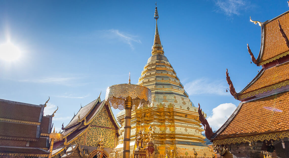 Wat Phra That Doi Suthep in Chiang Mai with a golden stupa and ornate temple buildings under a clear blue sky, showcasing Thailand’s rich religious architecture and cultural significance