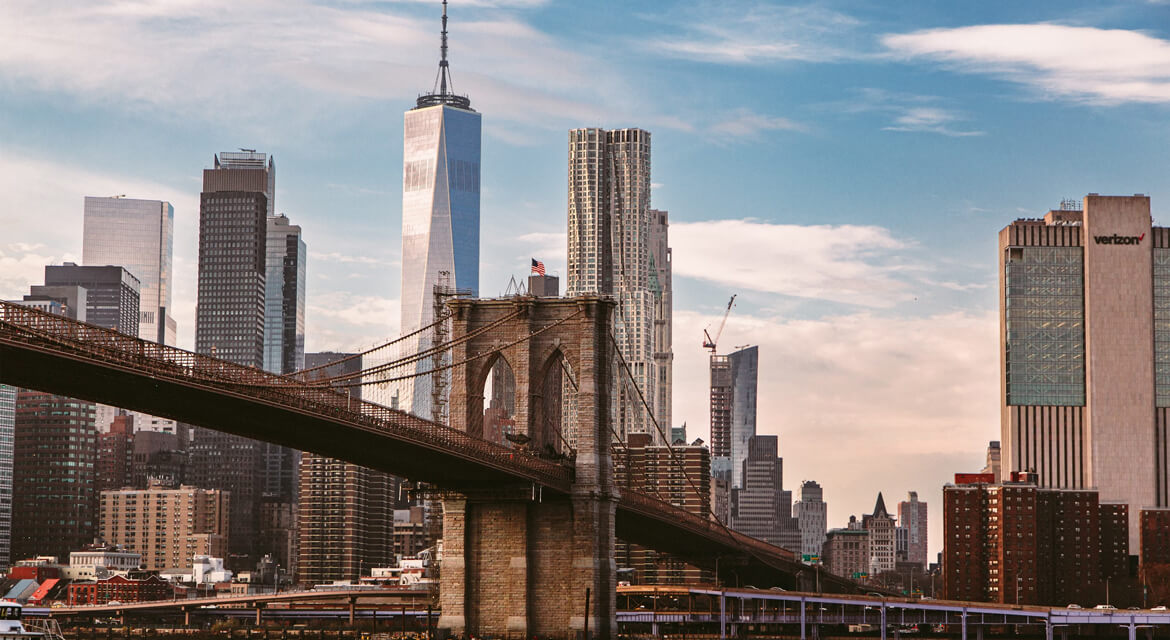 A scenic view of the Brooklyn Bridge with Manhattan’s skyline in the background, including One World Trade Center.