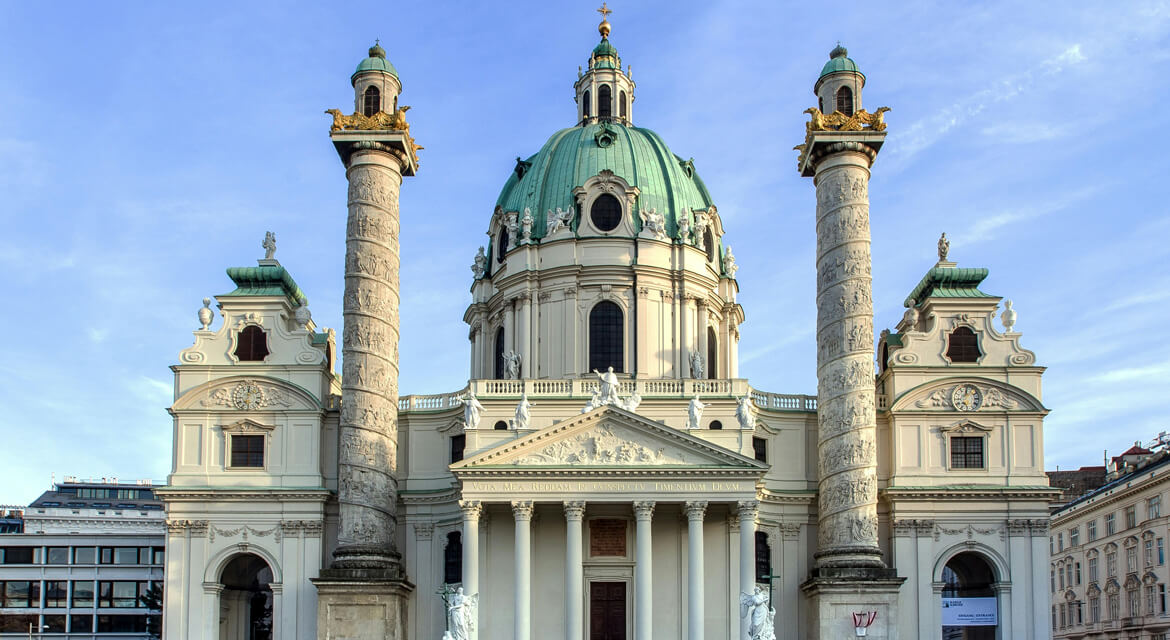 Karlskirche in Vienna with its grand baroque dome, ornate columns, and classical façade under a clear blue sky, reflecting Austria’s rich cultural heritage and café lifestyle